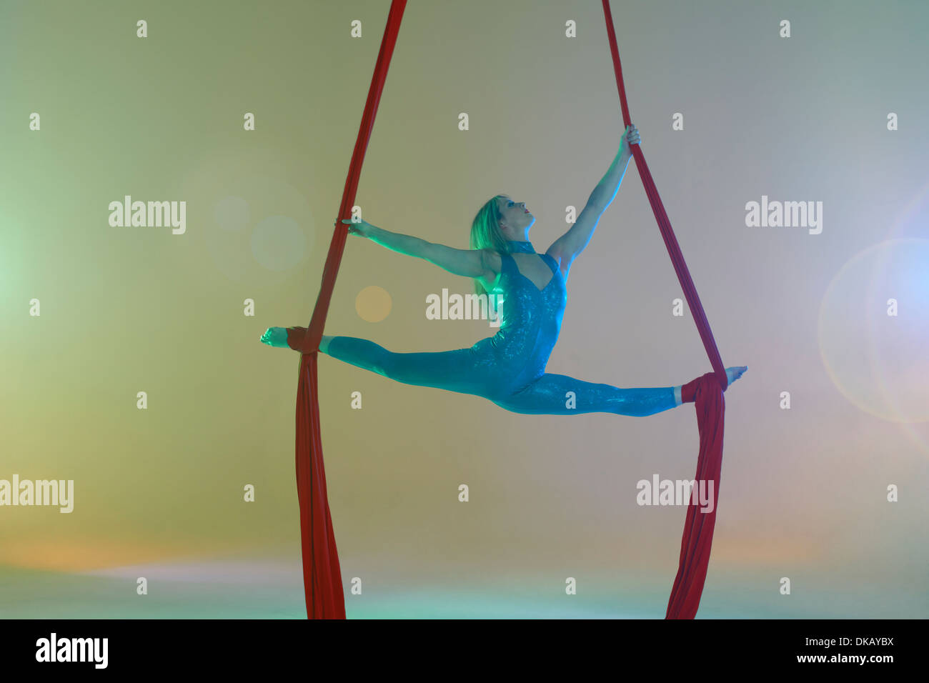 Aerial dancer doing the splits with red ribbon Stock Photo