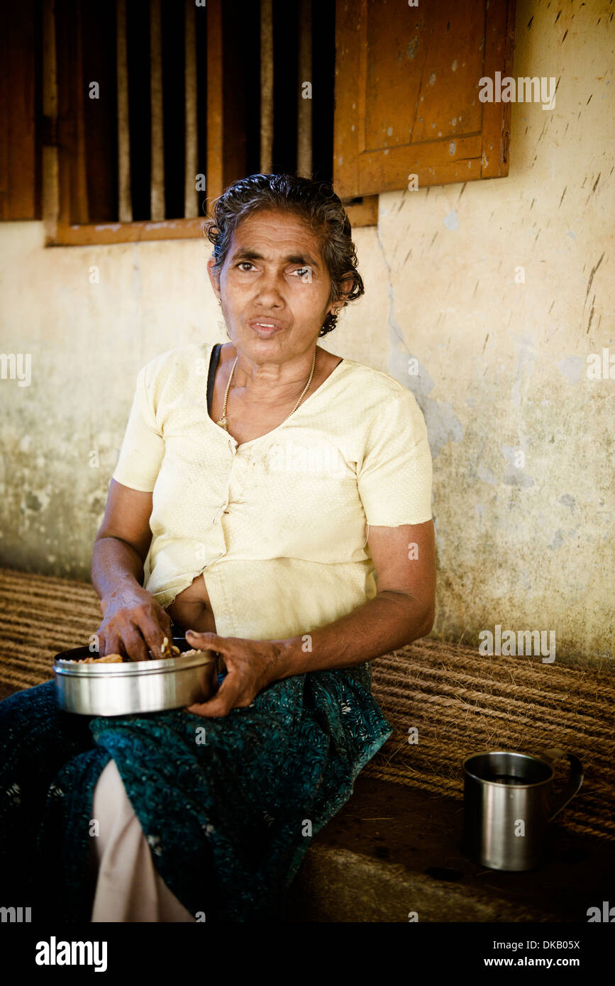 Woman eating her lunch. Making rope from coconut fibres. Munroe Island. Ashtamudi lake, Kollam, India Stock Photo