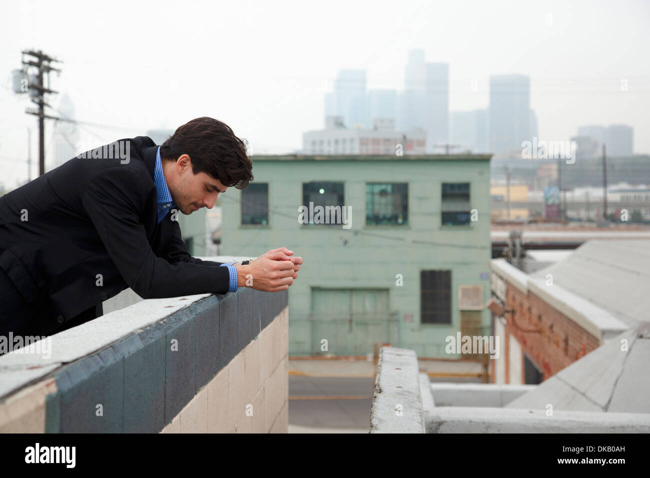 Unhappy young man looking down from city rooftop Stock Photo Alamy