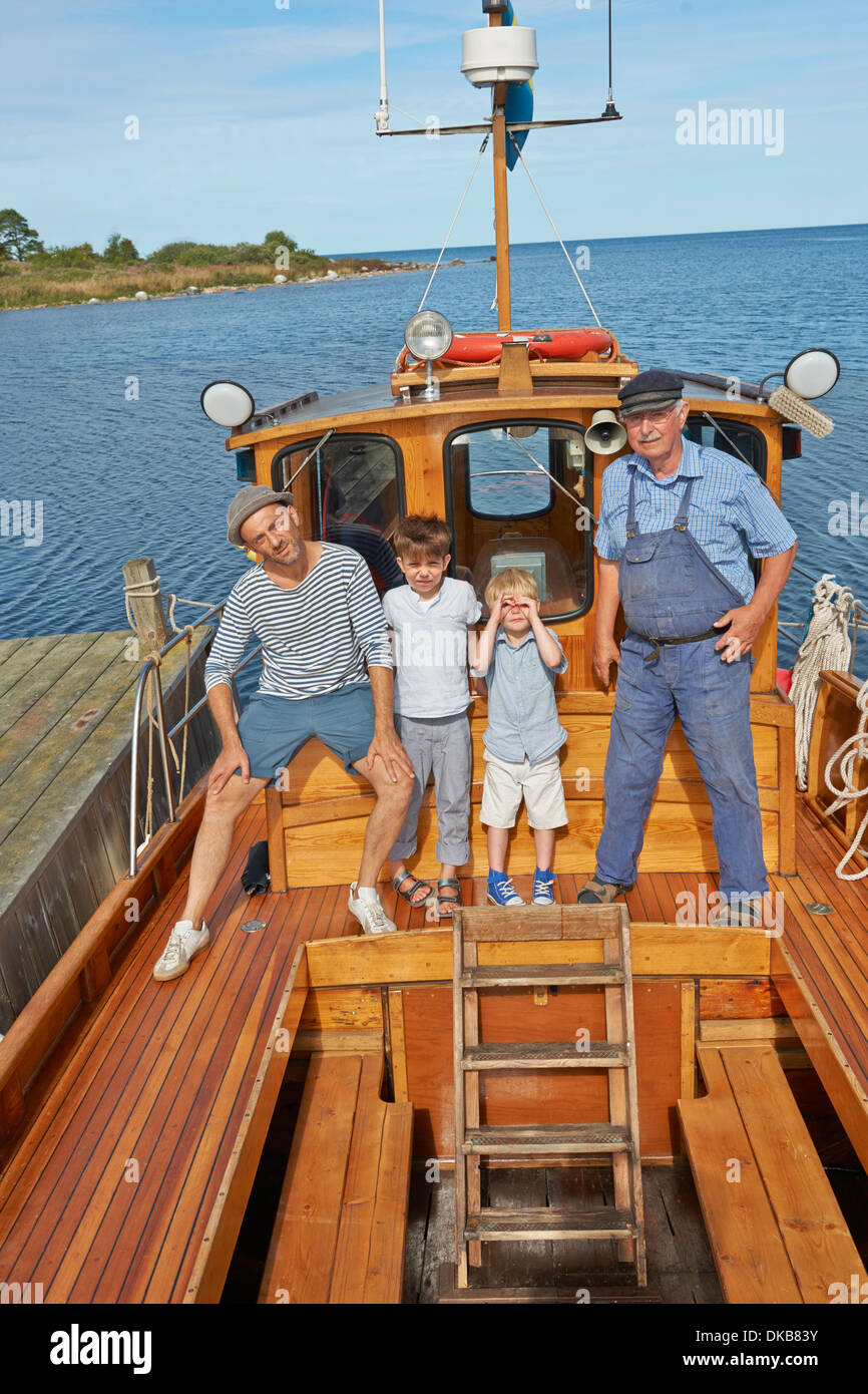 Father and two sons with fisherman on boat, Eggergrund, Sweden Stock Photo
