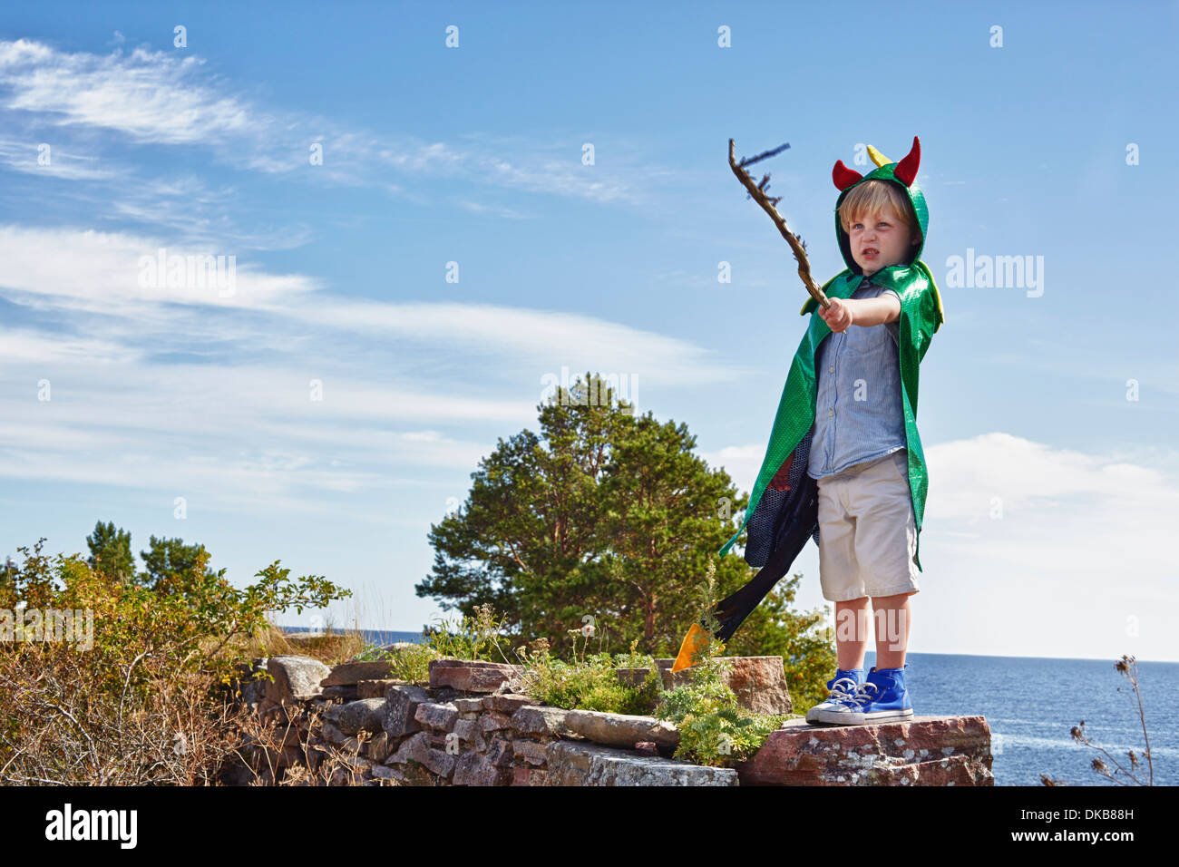 Boy wearing green cape holding stick, Eggergrund, Sweden Stock Photo