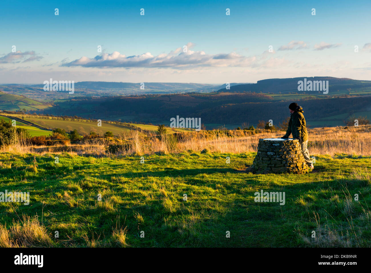 A rambler pauses to admire the view from the toposcope on Bury Ditches Iron Age hill fort in South Shropshire near Clun, England Stock Photo