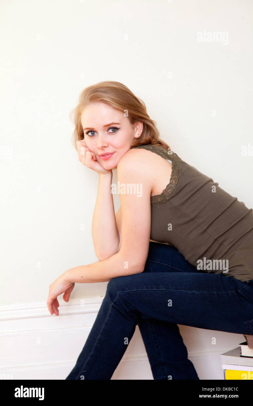 Young woman sitting on pile of books Stock Photo - Alamy