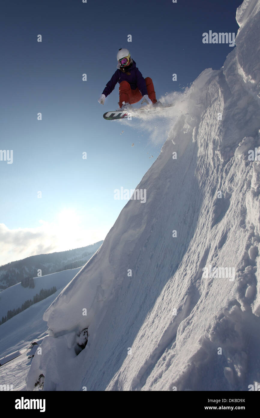 Snowboarder jumping down mountain Stock Photo