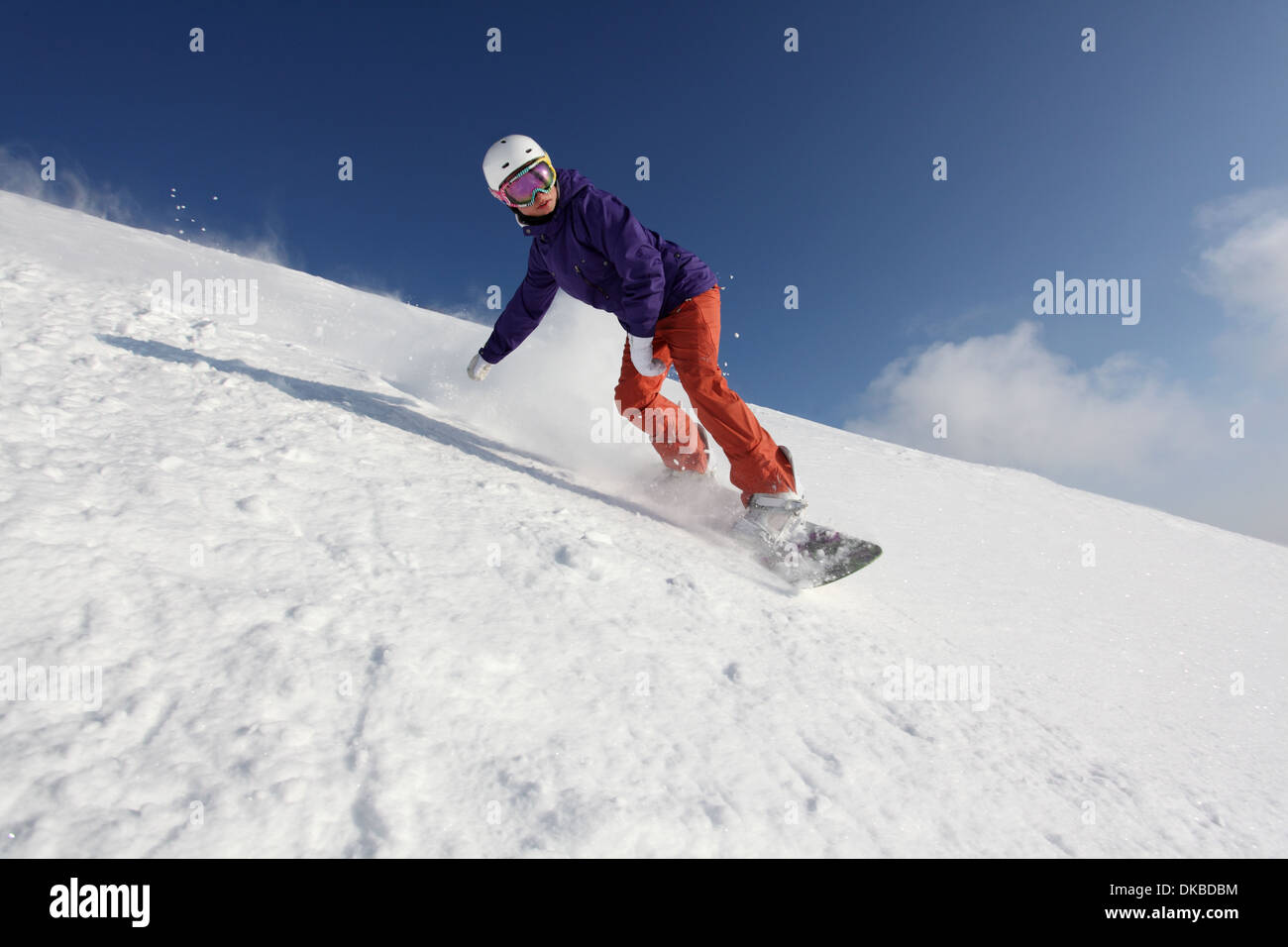 Snowboarder going down mountain Stock Photo