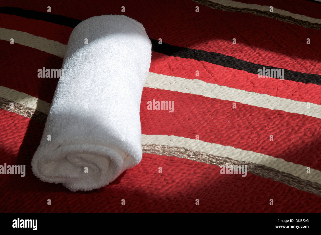 Rolled white towel on bed. Stock Photo