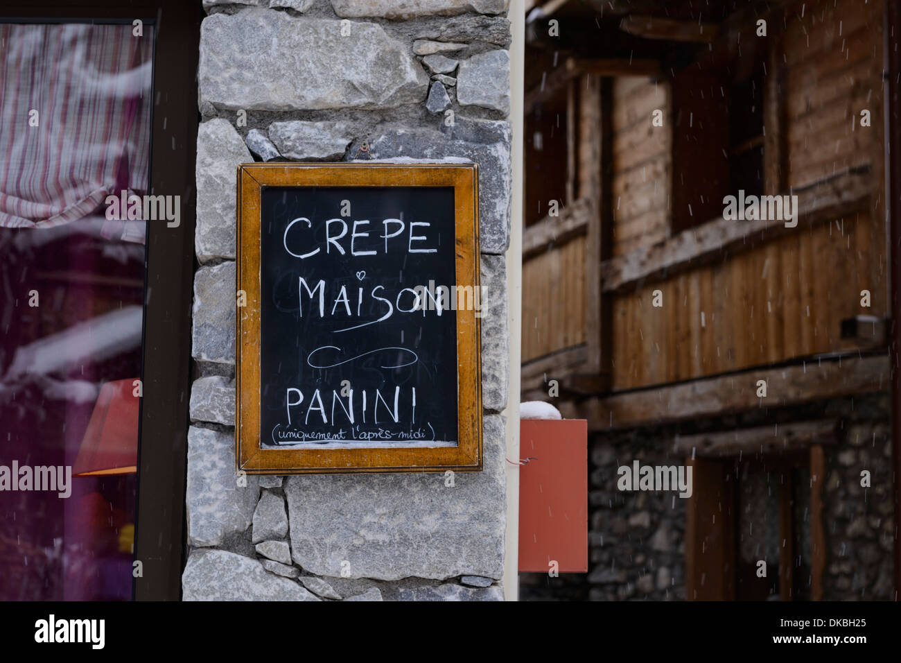 Outdoor blackboard sign on a stone wall with a rustic wooden building in the background Stock Photo
