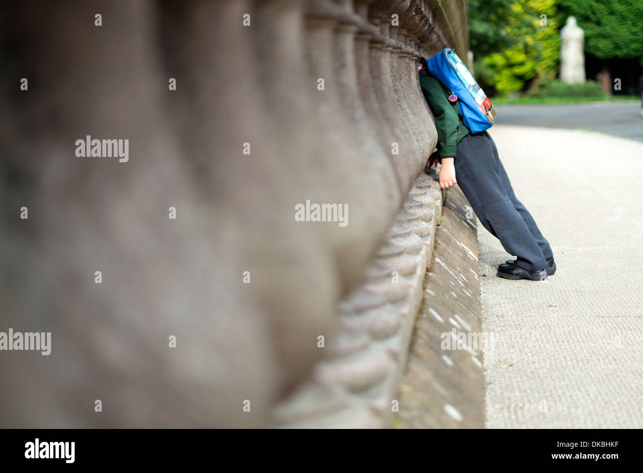 A small child in school uniform looks through a gap in a bridge over the River Kelvin in Glasgow, Scotland. Stock Photo