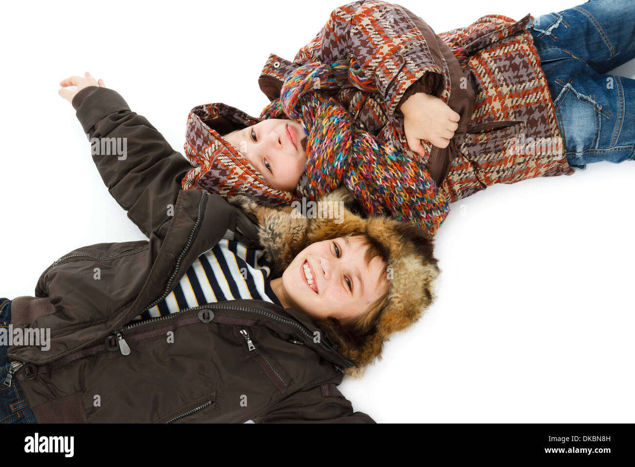 two boys dressed in winter jackets lying on snow Stock Photo Alamy