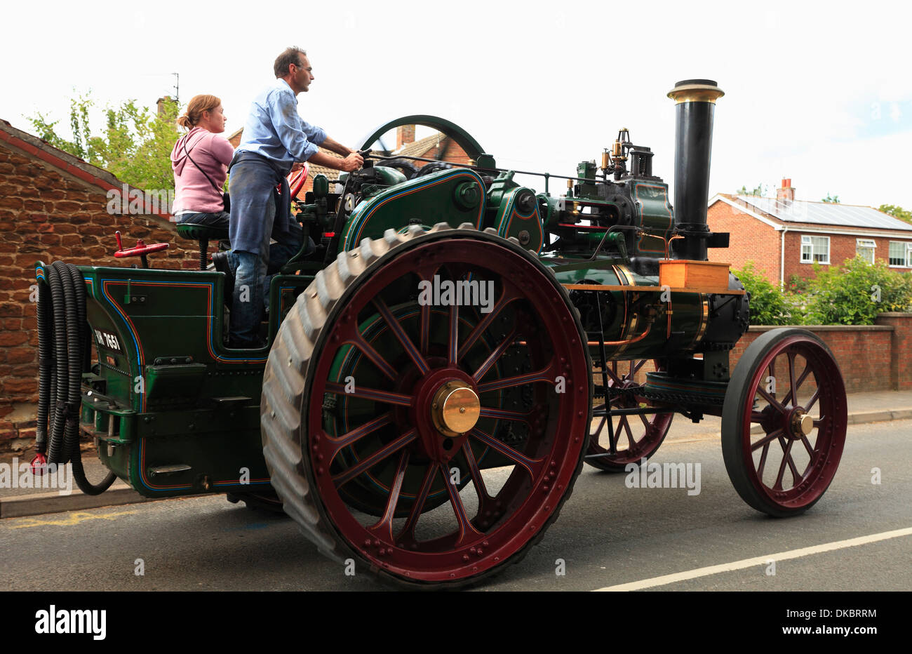 Man and a woman drive traction engine 'Valiant' through the village of Heacham, Norfolk to a steam rally. Stock Photo