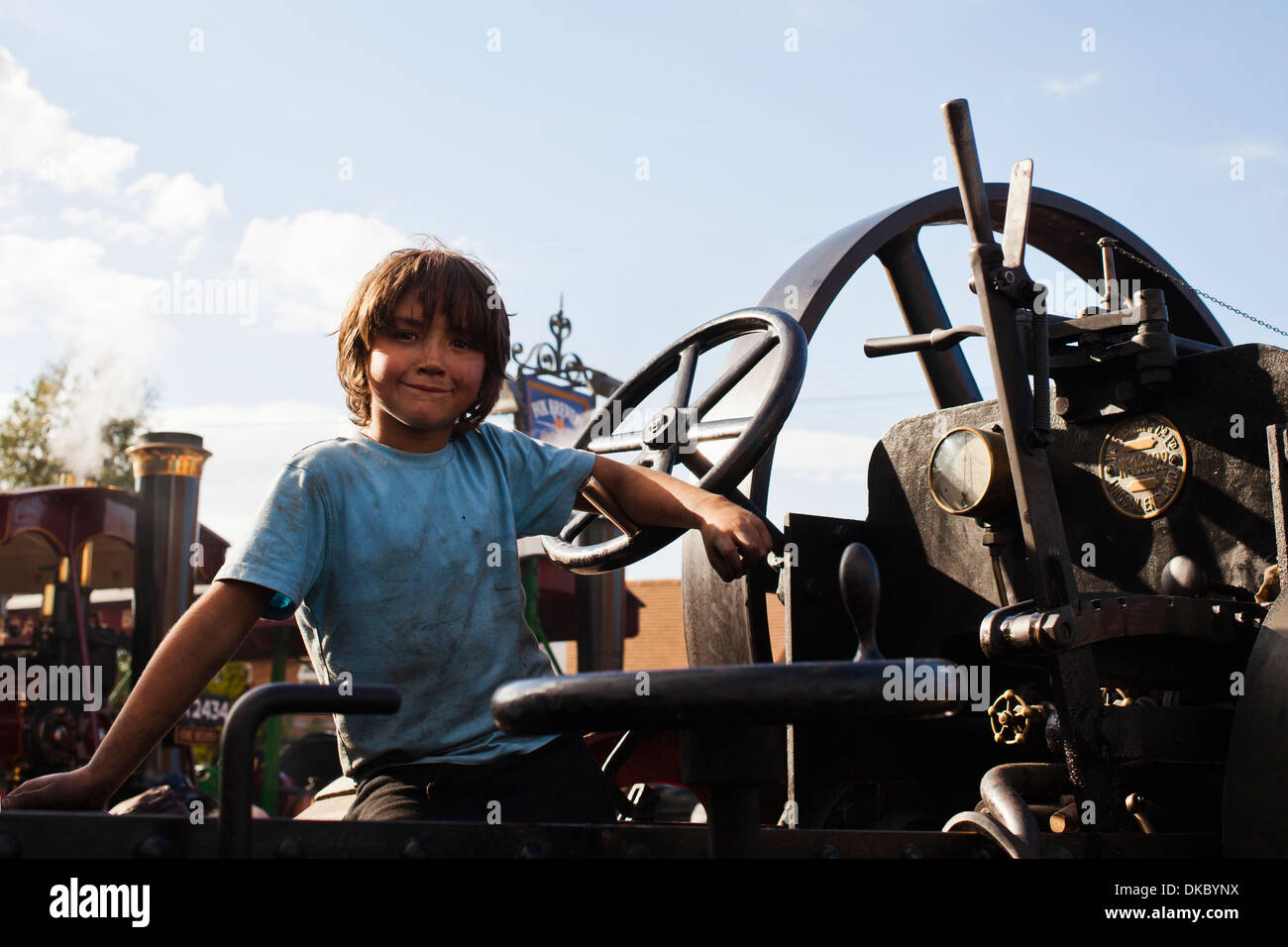 A young boy at the wheel of a traction engine at a steam rally at Heacham, Norfolk, UK. Stock Photo