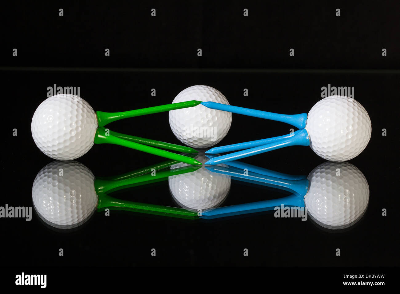 White Golf Balls And Different Colored Tees On A Black Desk Stock