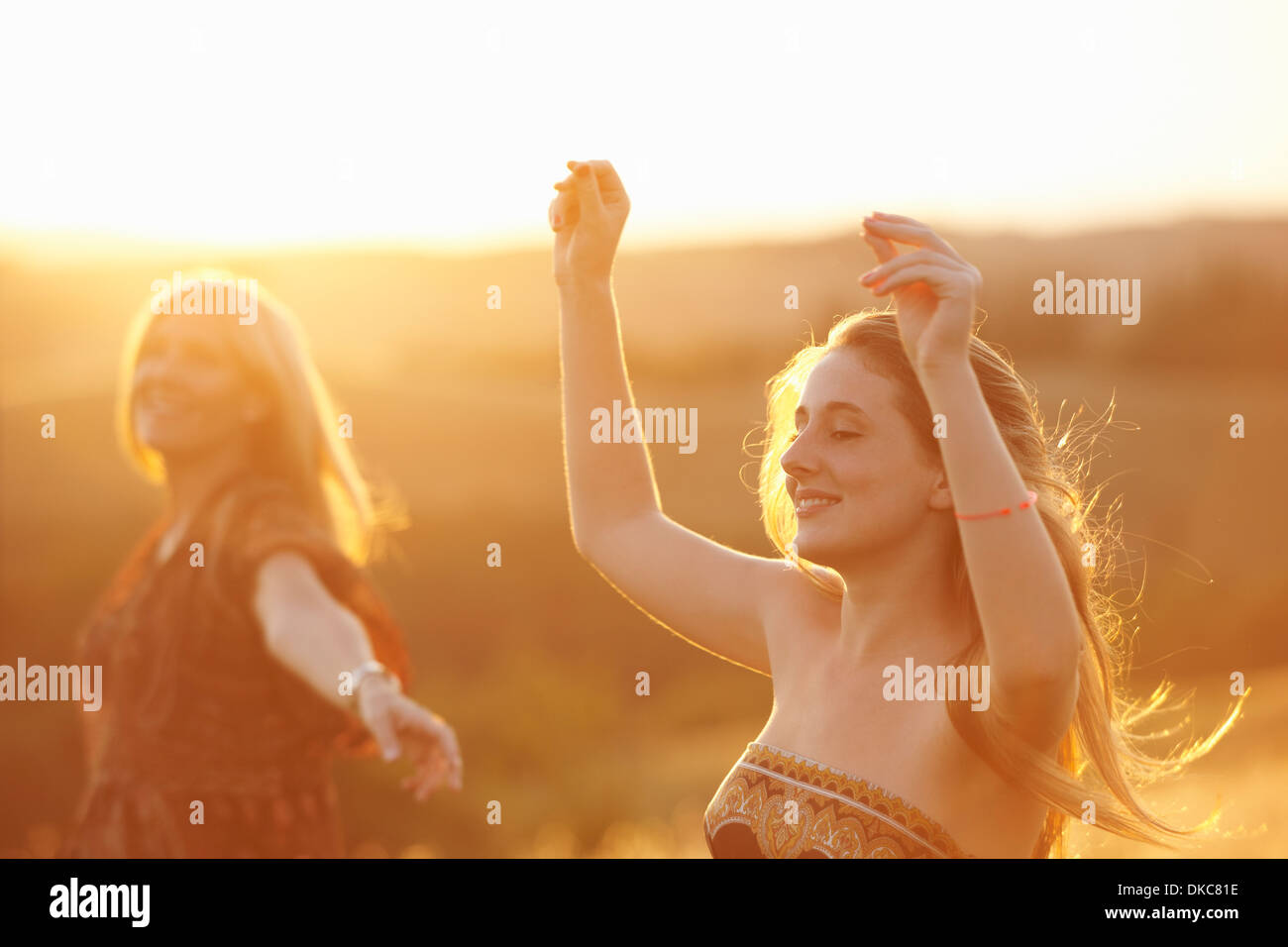 Woman and teenager dancing in field at dusk Stock Photo