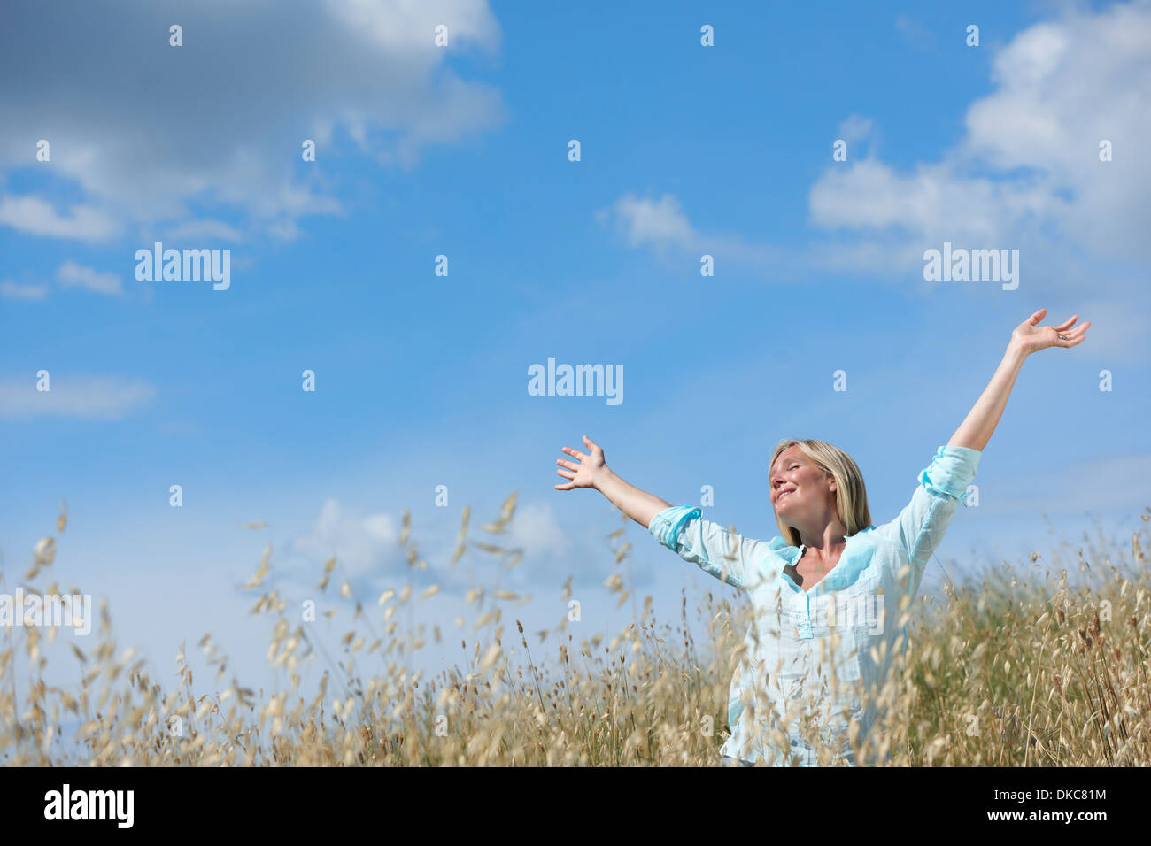Woman standing in corn field with arms raised Stock Photo