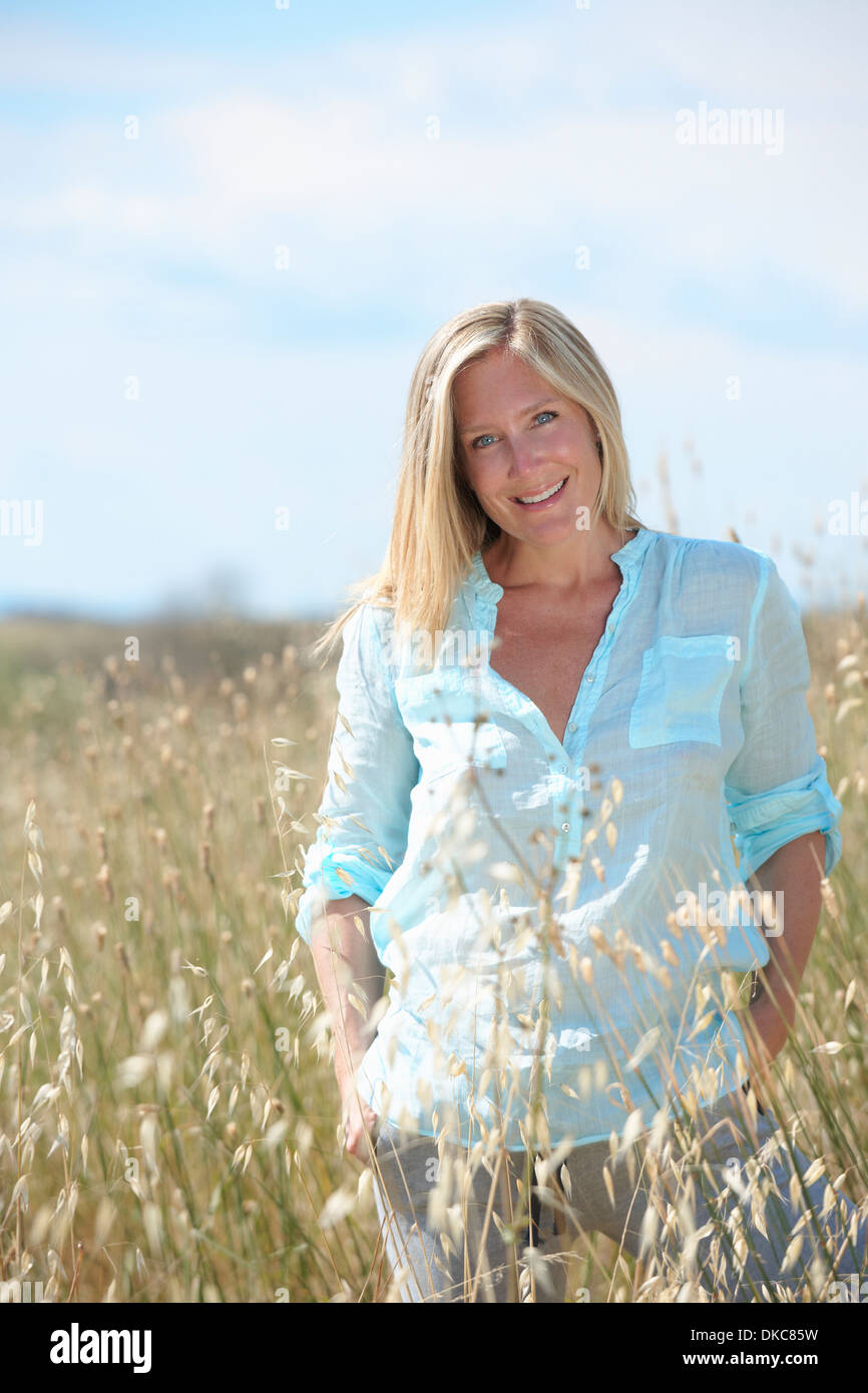 Woman standing in field with hands in pockets Stock Photo
