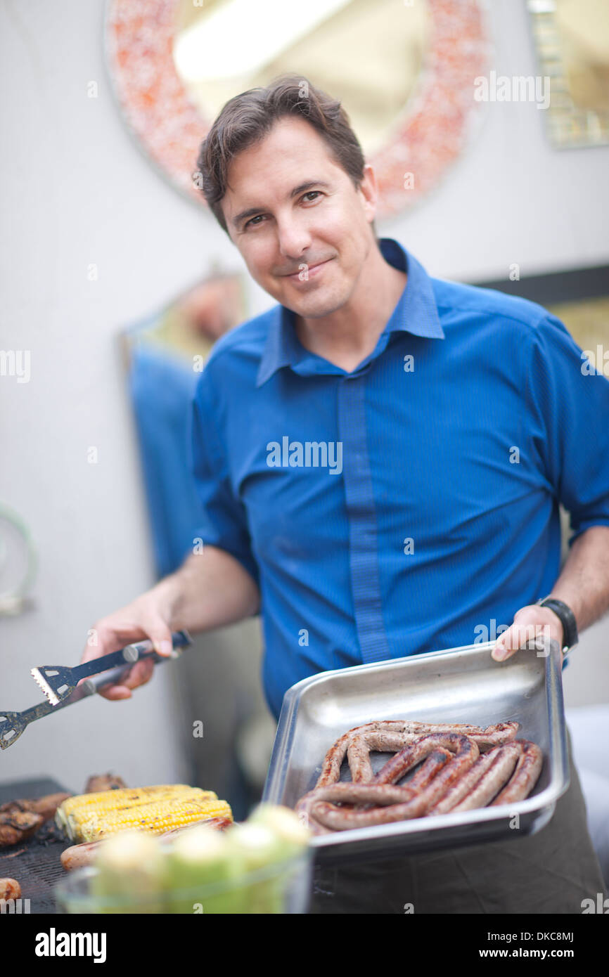 Mature man barbecuing sausages Stock Photo