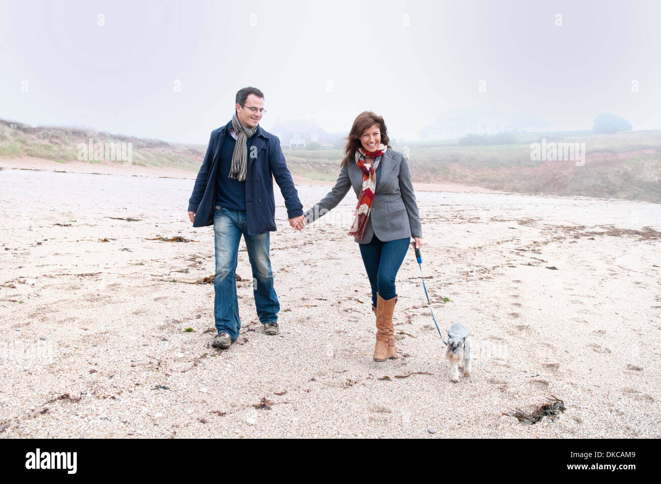 Couple walking with dog on beach, Thurlestone, Devon, UK Stock Photo