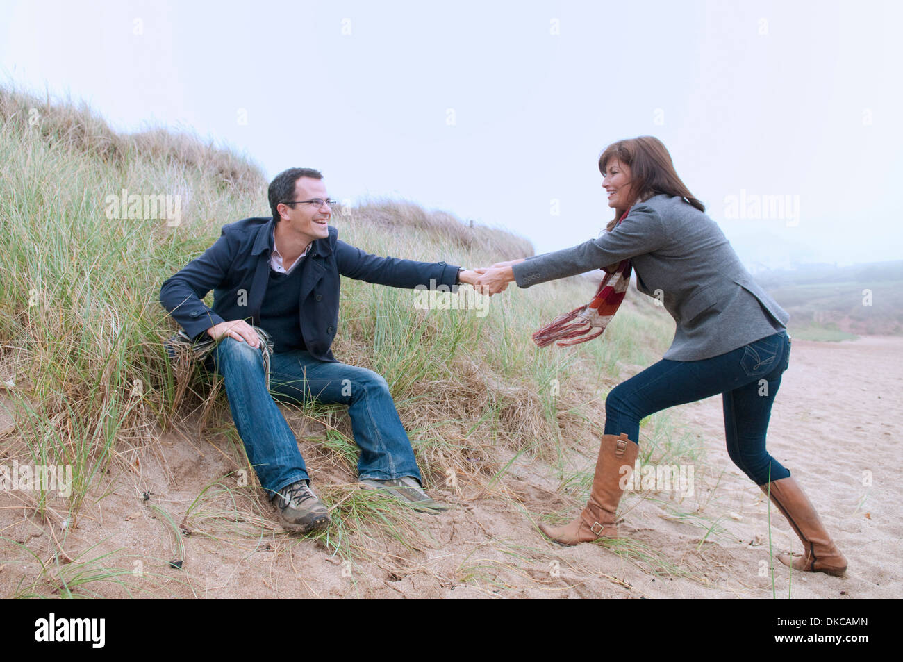 Couple getting up from sand dune Stock Photo