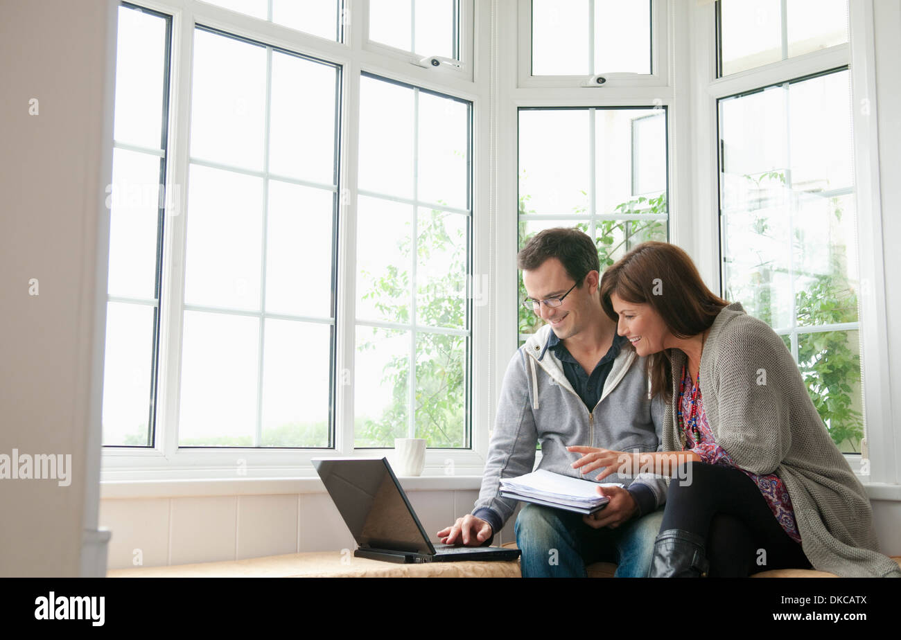 Couple on window seat, using laptop Stock Photo