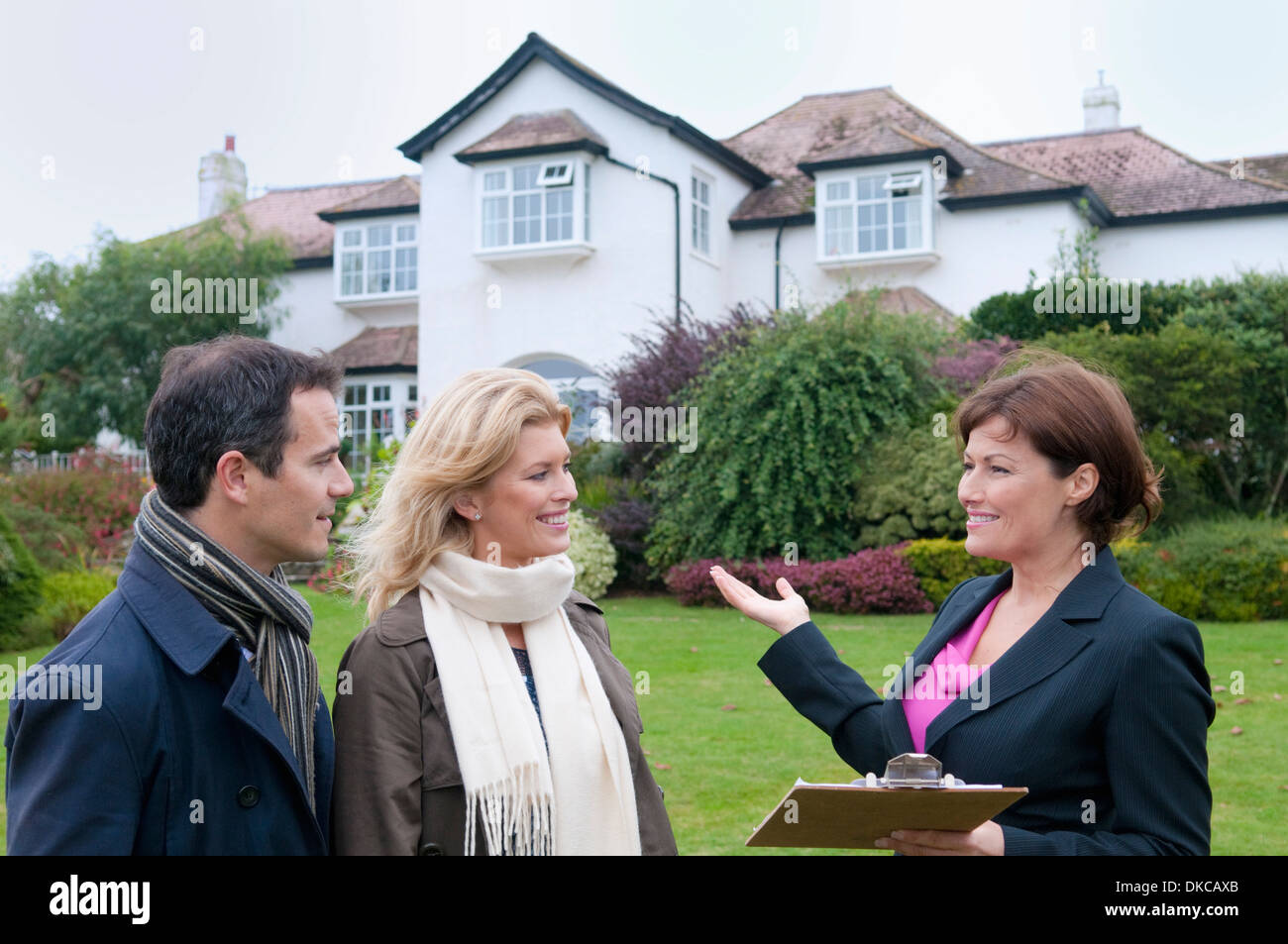Mid adult couple and female estate agent outside house Stock Photo