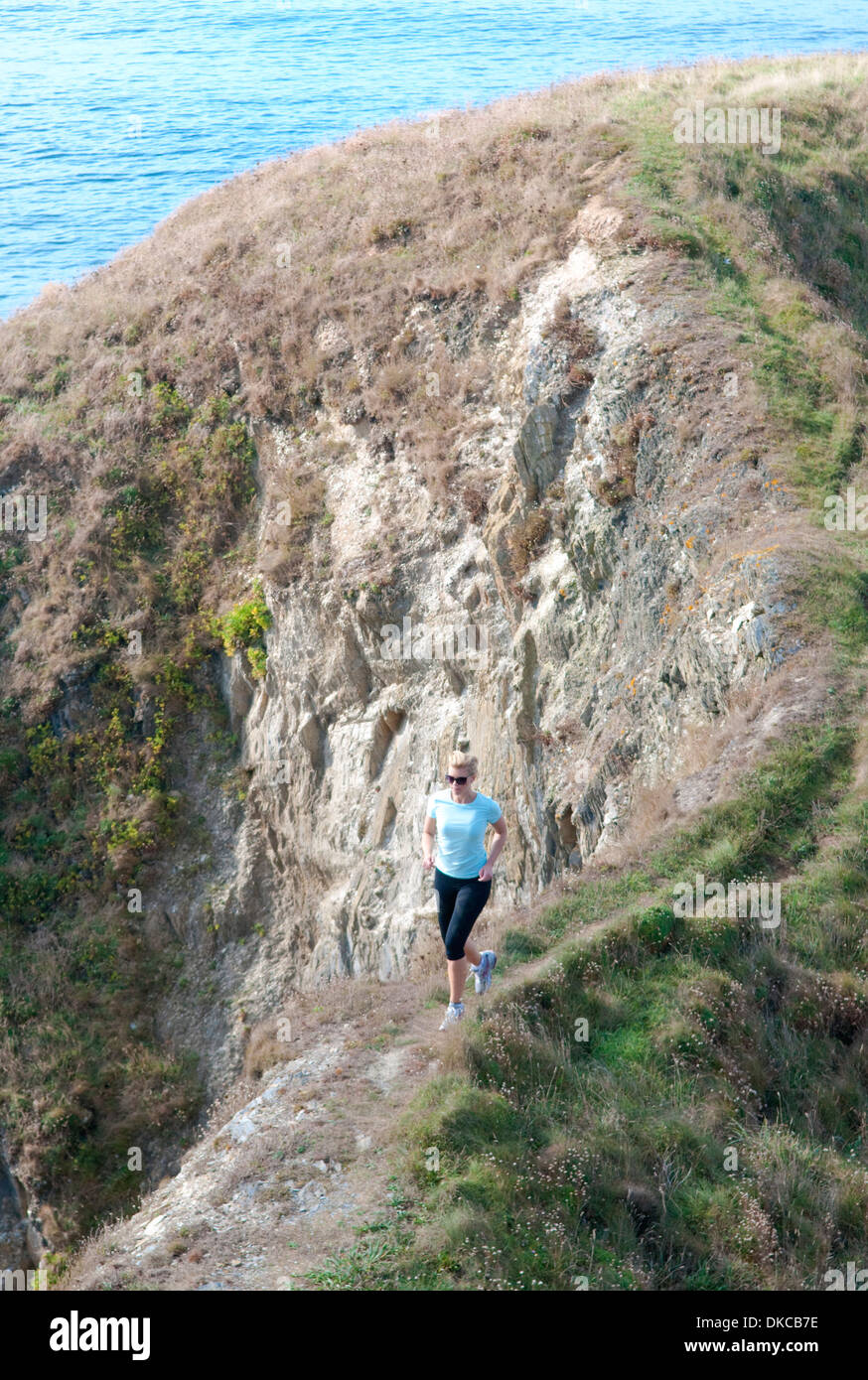 Mid adult woman jogging on coastal path, Thurlestone, Devon, UK Stock Photo