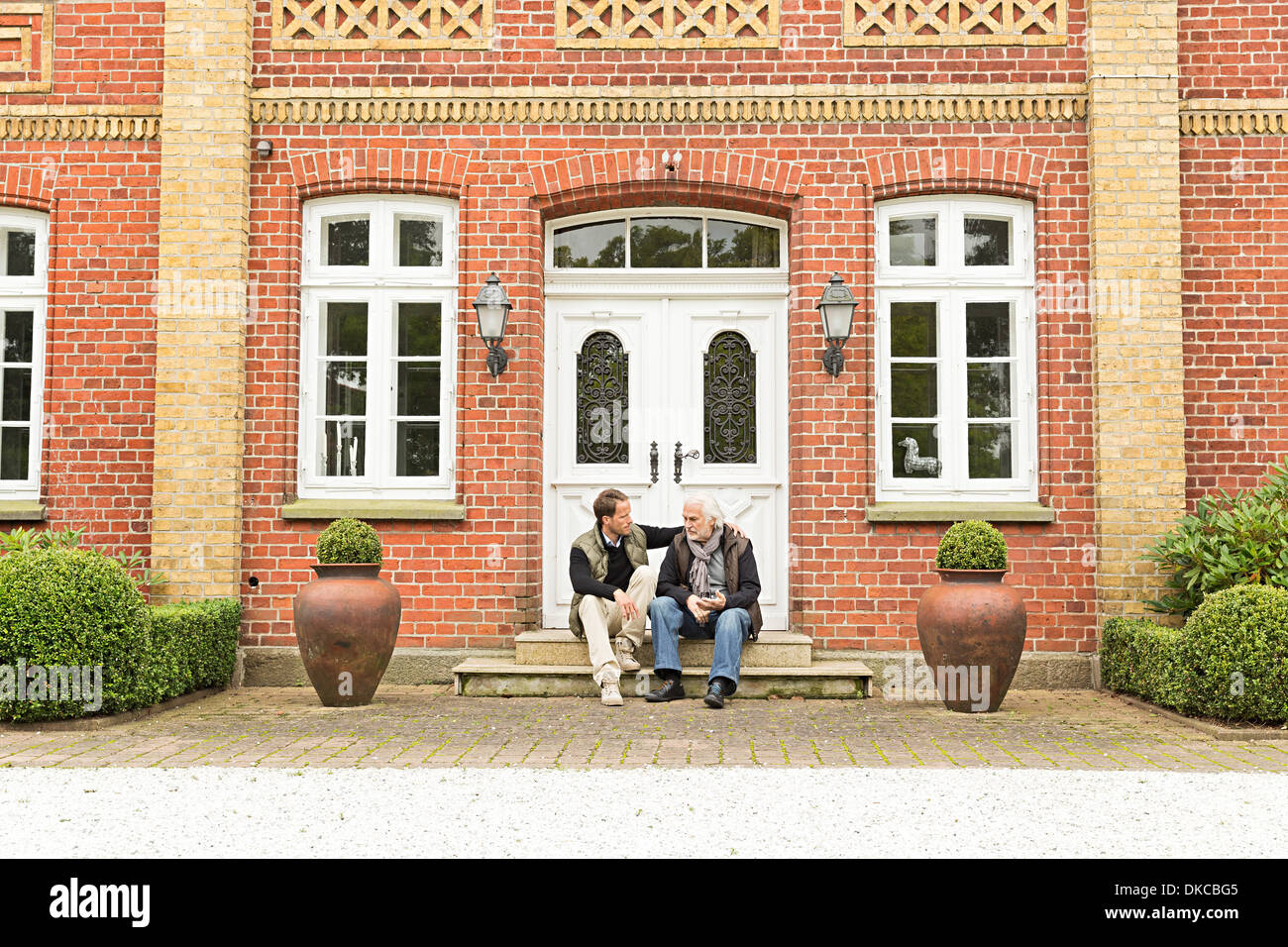 Father and son sitting on doorstep Stock Photo