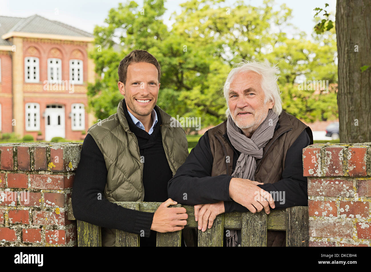 Father and son leaning on wooden gate Stock Photo