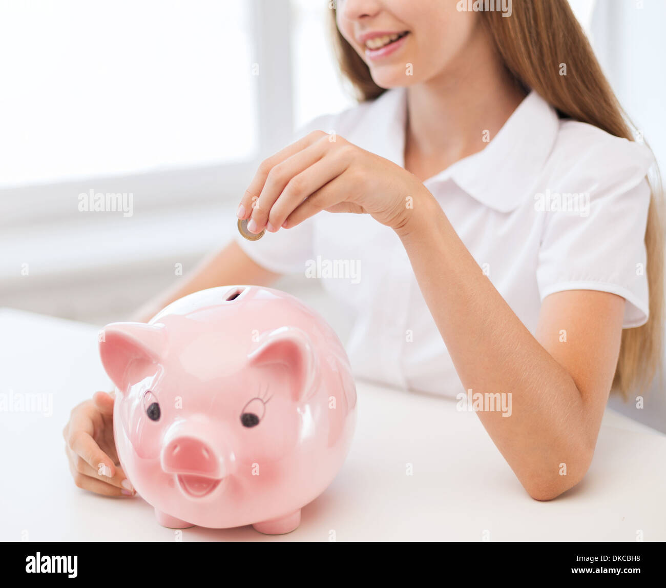 smiling child putting coin into big piggy bank Stock Photo Alamy