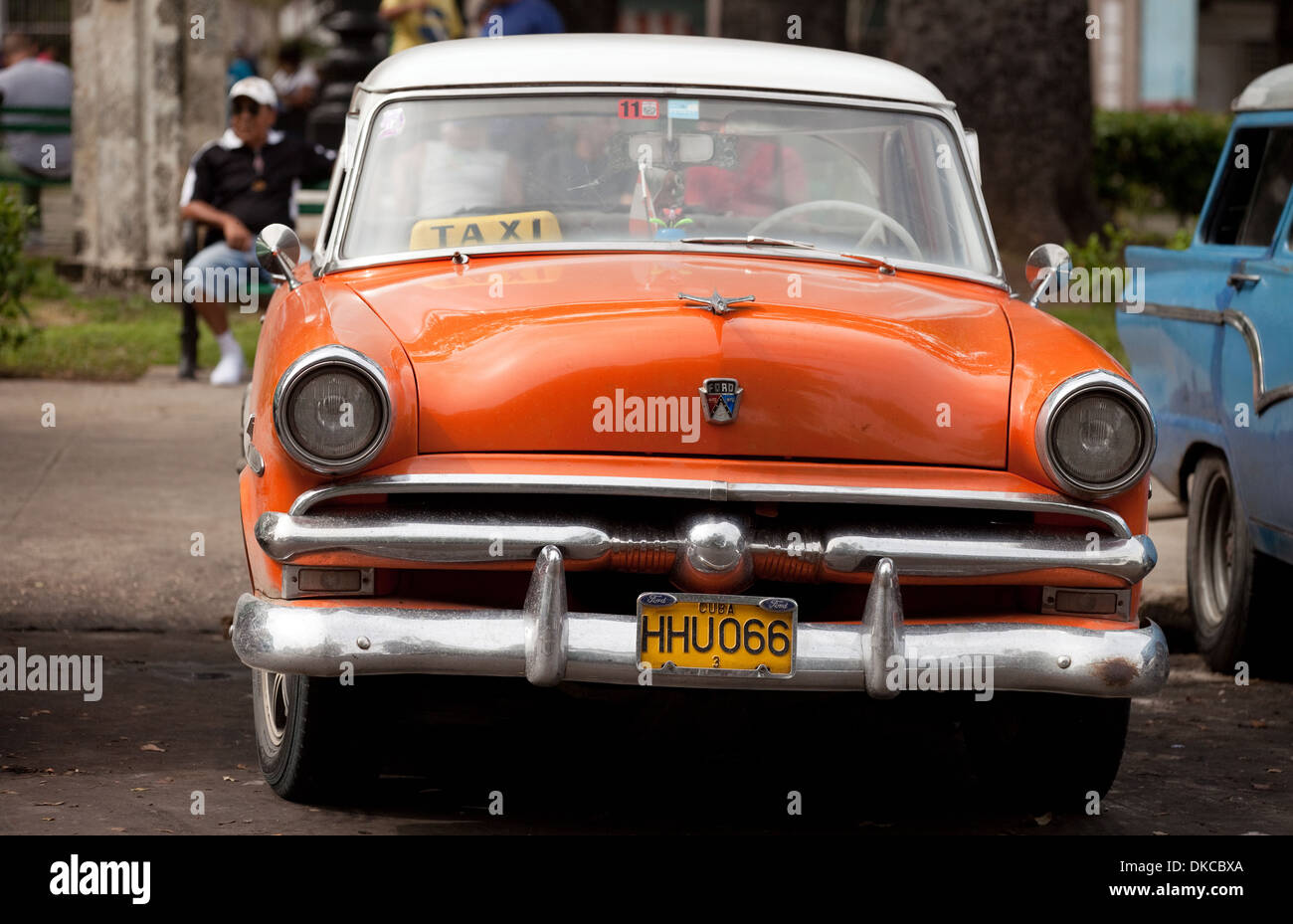 Old orange american car used as a taxi, with taxi driver sitting in the  background, Havana, Cuba, Caribbean Stock Photo - Alamy