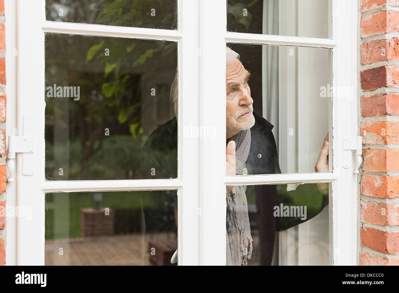 Senior man looking through window Stock Photo