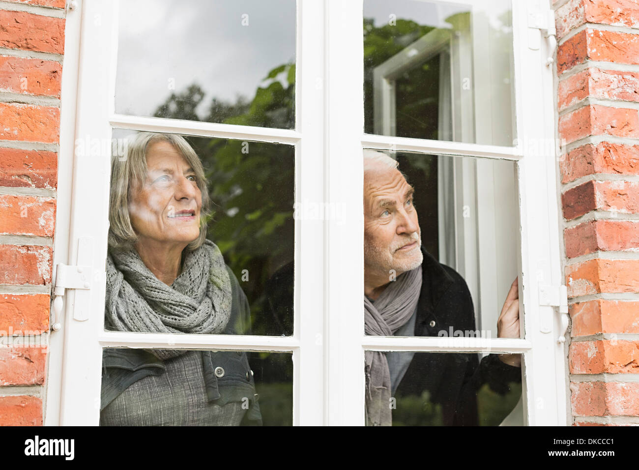 Senior couple looking through window Stock Photo