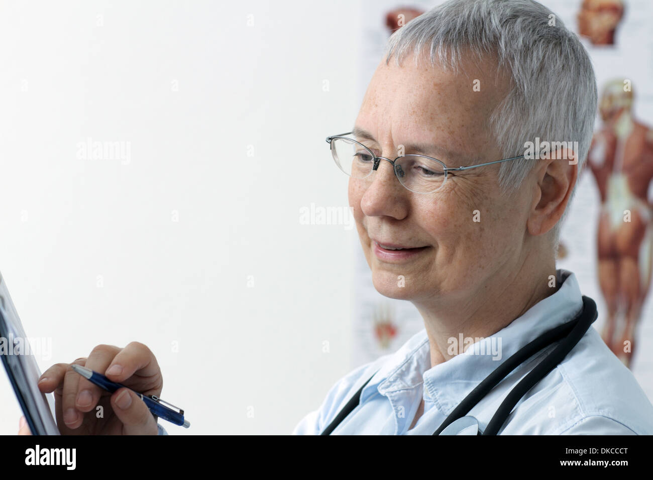 a laughing  woman doc with a human muscle person poster in the background and with a pen on laptop or desktop Stock Photo