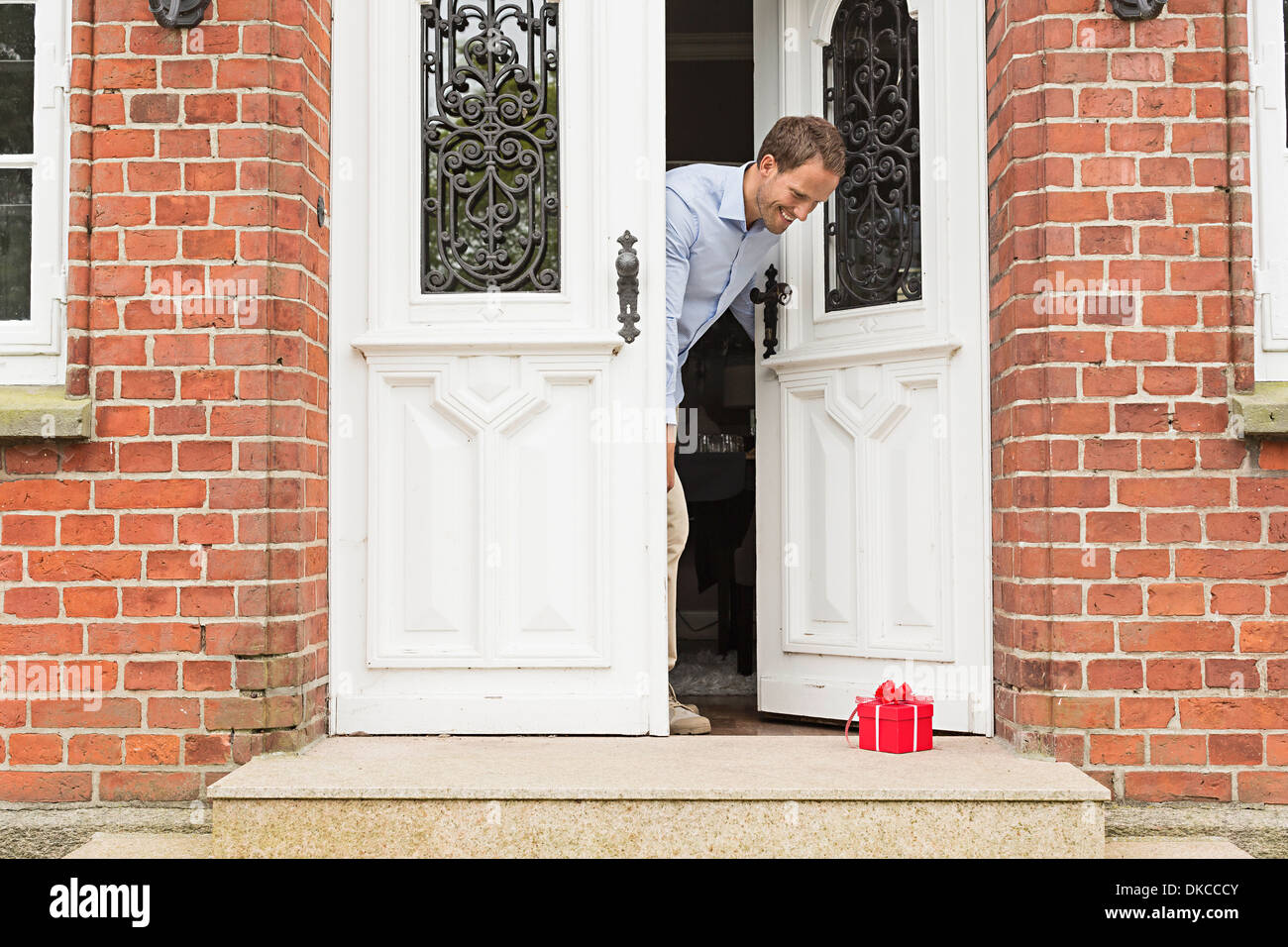 Mid adult man with gift on front doorstep Stock Photo