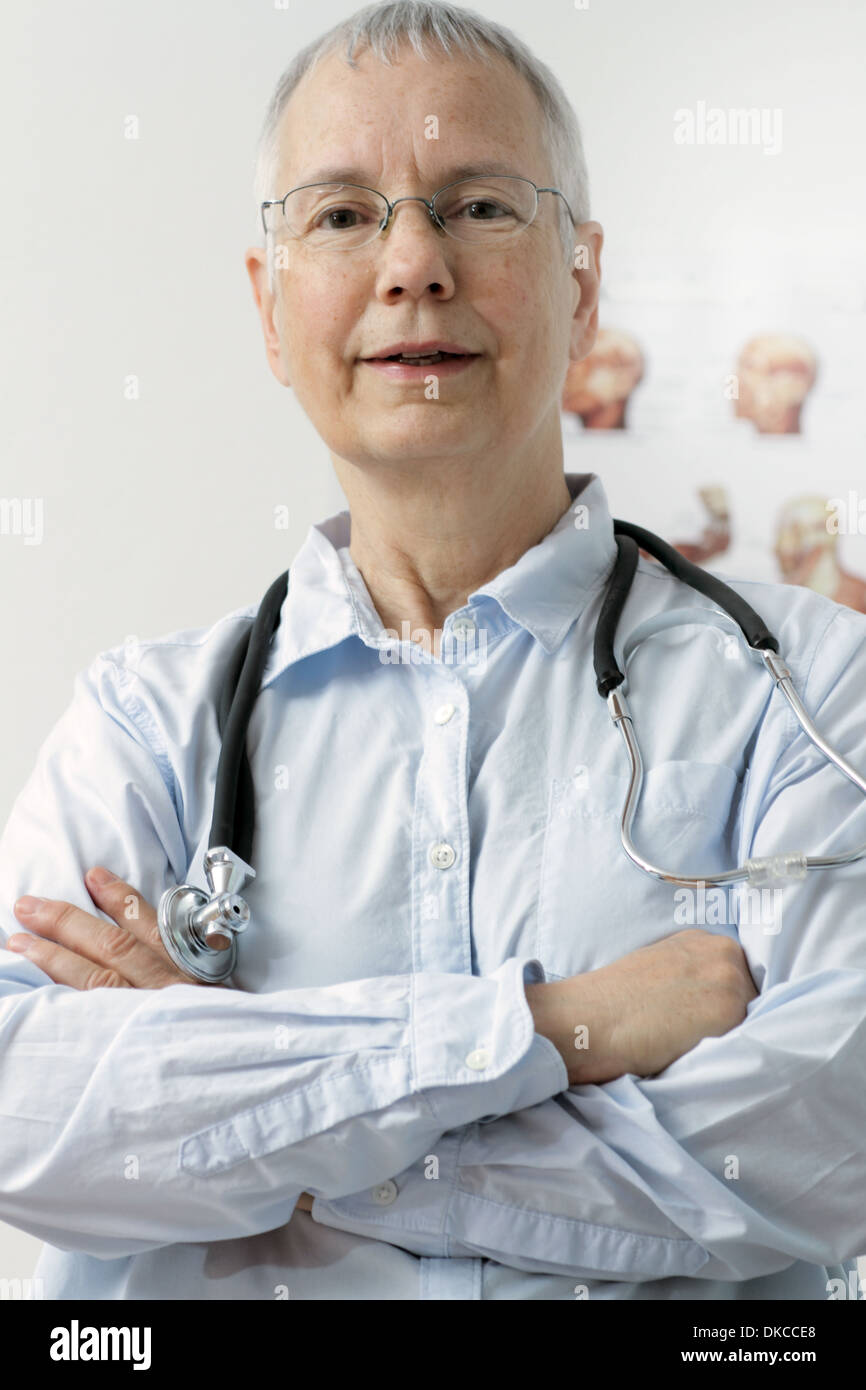 a friendly looking woman doc with a human muscle person poster in the background and a laptop Stock Photo