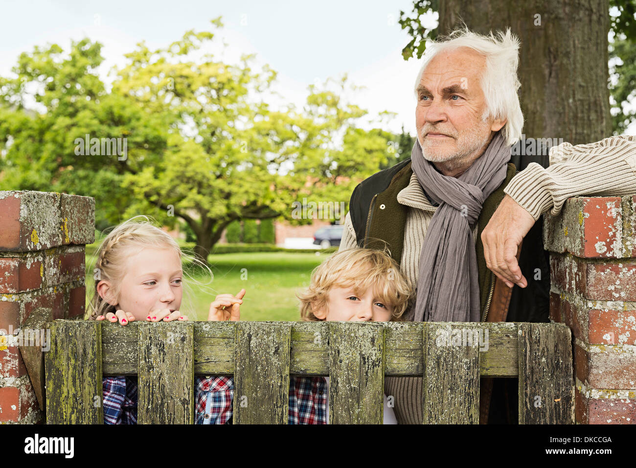 Grandfather and grandchildren by wooden gate Stock Photo