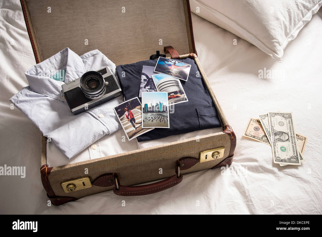 Open suitcase on bed with camera and photographs Stock Photo Alamy