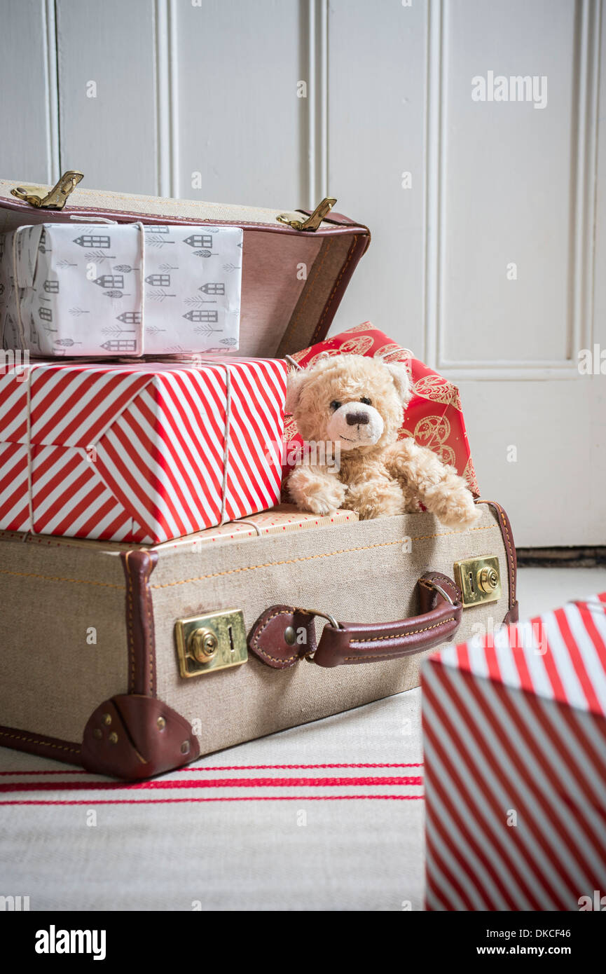 Suitcase filled with wrapped gifts and teddy bear Stock Photo