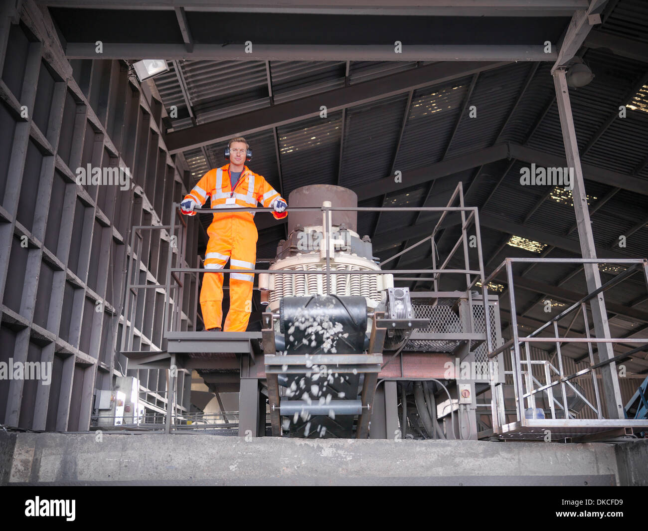 Worker in reflective workwear operating metal crushing machine Stock Photo