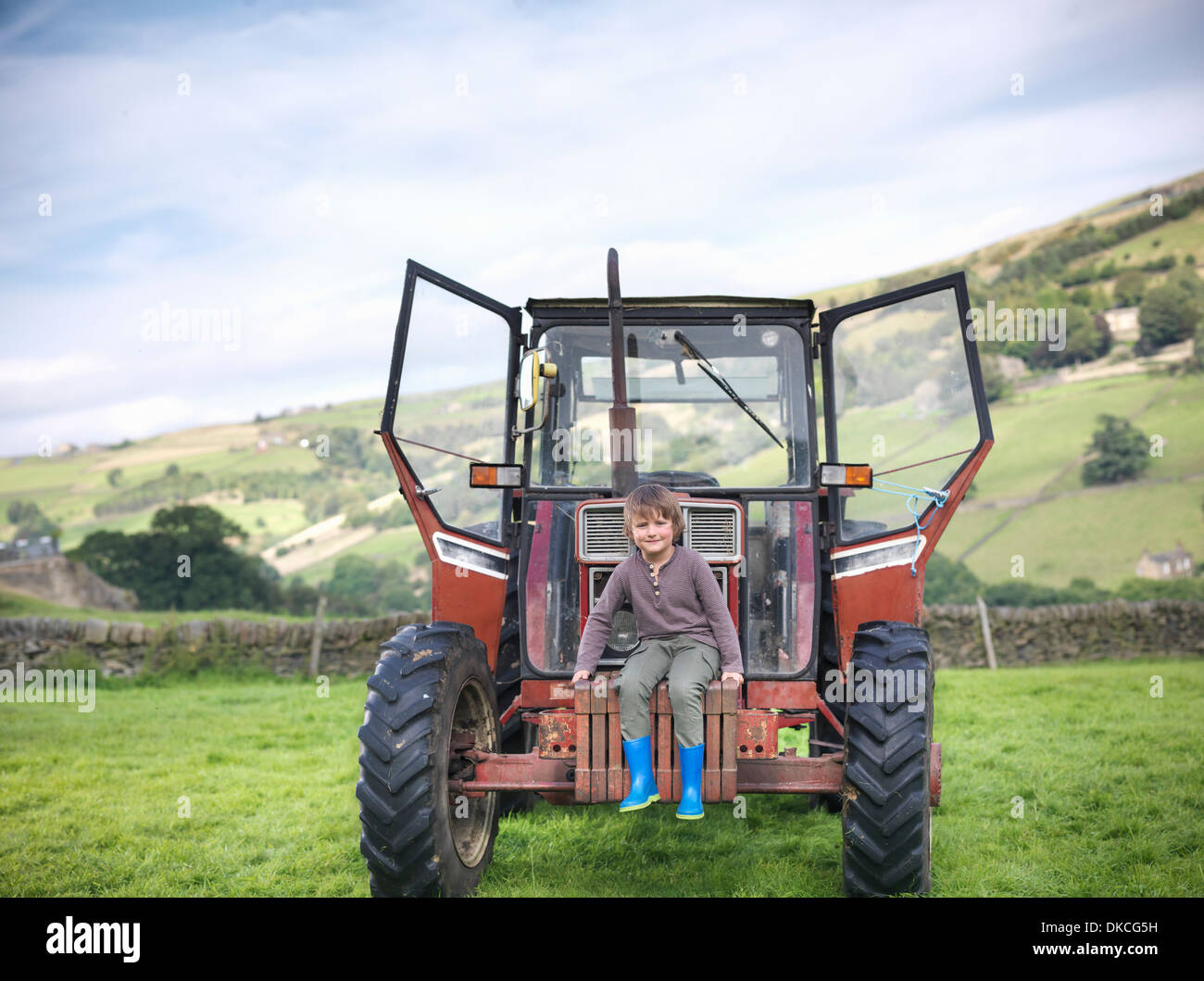 Farmer's son sitting on tractor in field, portrait Stock Photo
