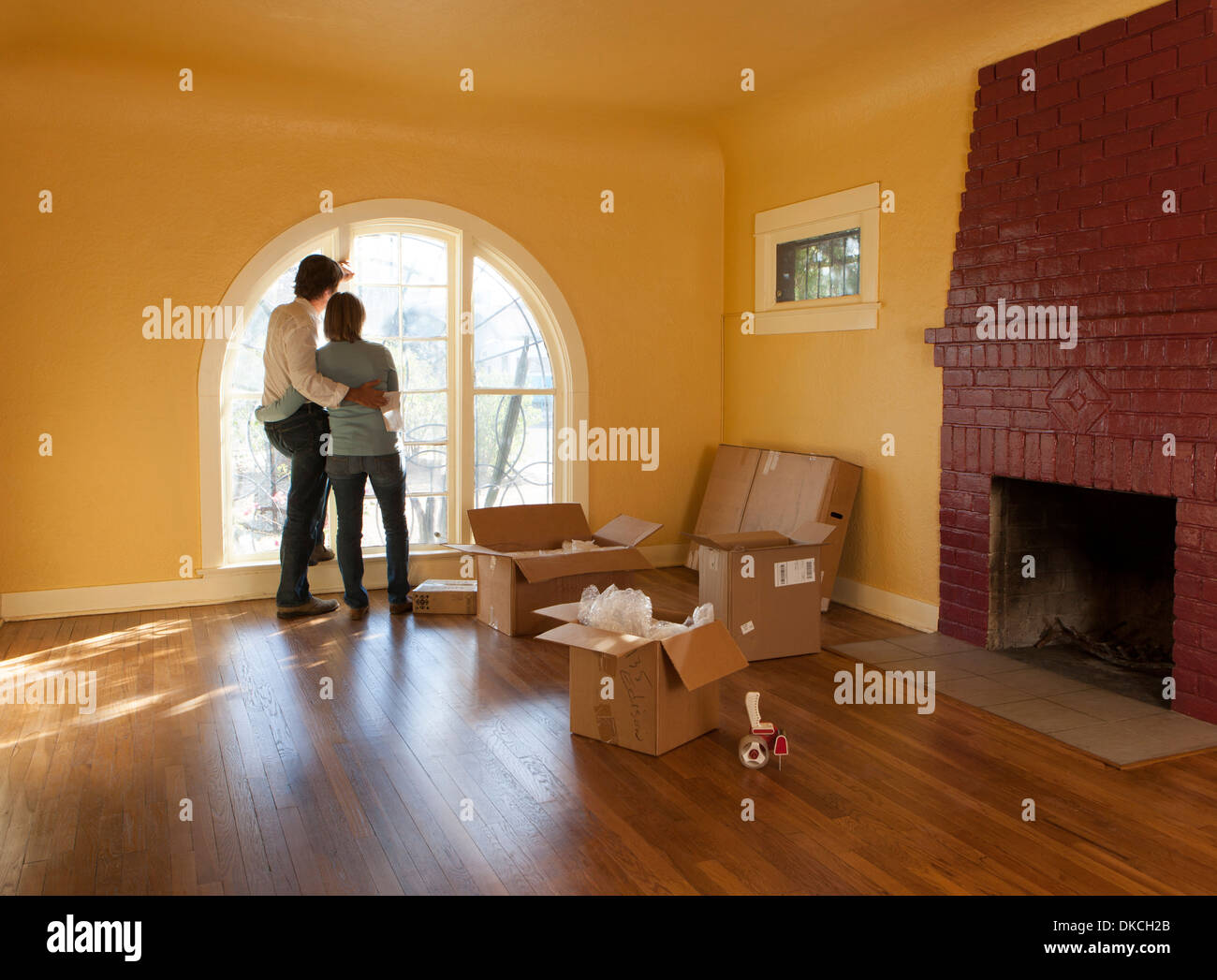 A couple in an empty room in a residential house with cardboard boxes suggesting they are moving in or out. Stock Photo
