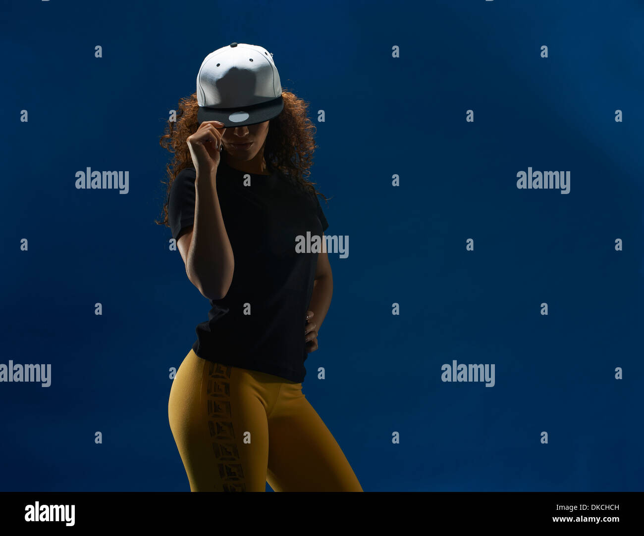 Studio portrait of young woman tipping her baseball cap Stock Photo Alamy