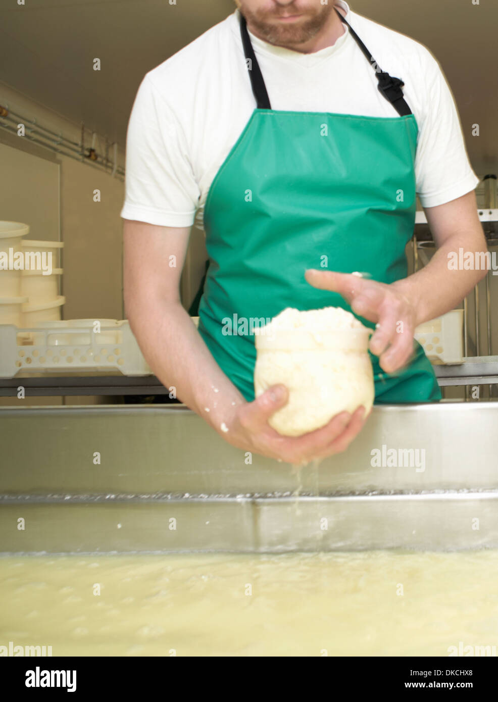 Cheesemaker moulding curds at farm factory Stock Photo