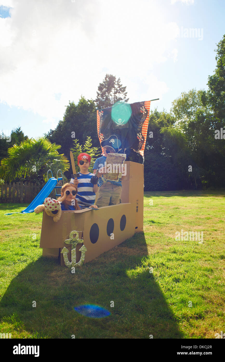 Two brothers and sister playing in garden with homemade pirate ship Stock Photo
