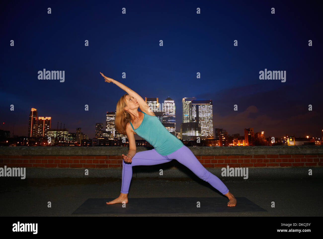 Mid adult woman doing yoga on city rooftop Stock Photo