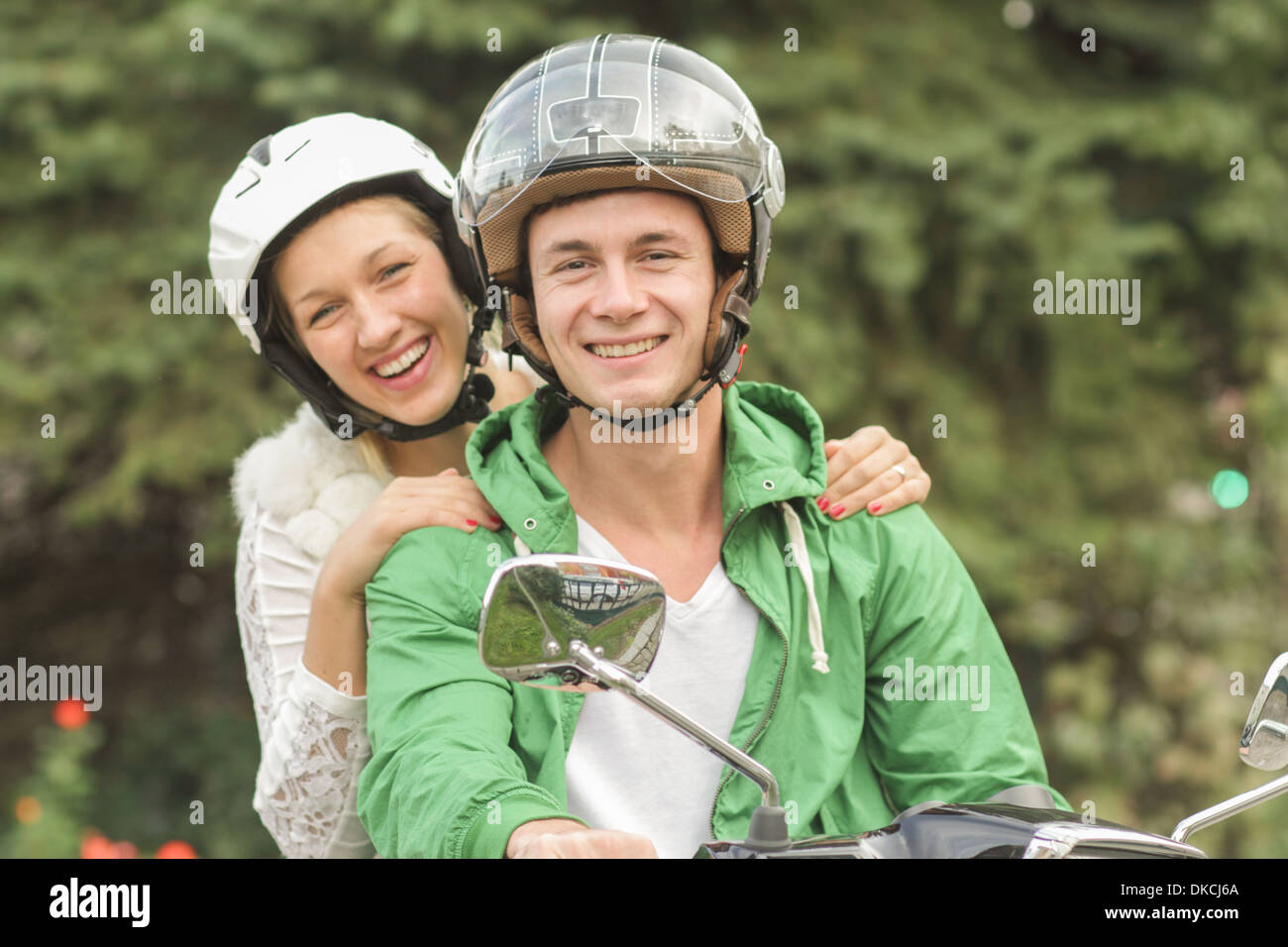 Portrait of young couple in helmets sitting on vespa Stock Photo