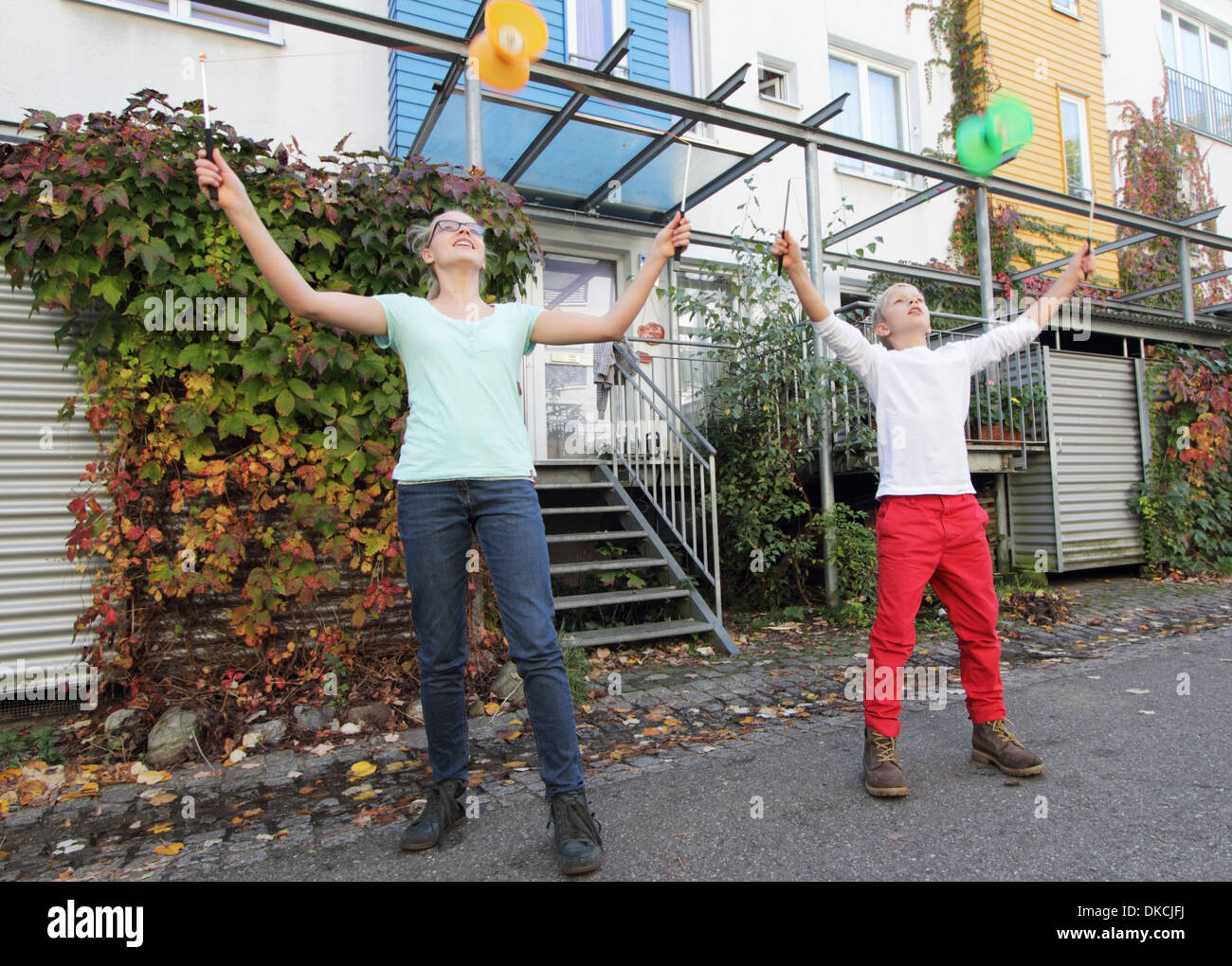 Brother and sister playing with spinning tops outside house Stock Photo -  Alamy