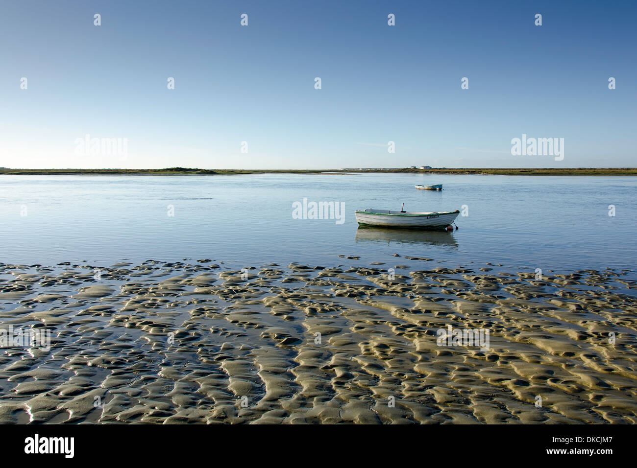 Tidal flat with small boats on a lagoon and water, mud and sand Stock