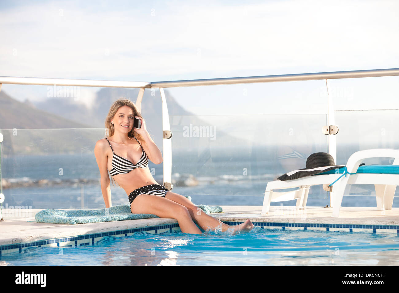 Woman using cellular phone by swimming pool, Cape Town, South Africa Stock Photo