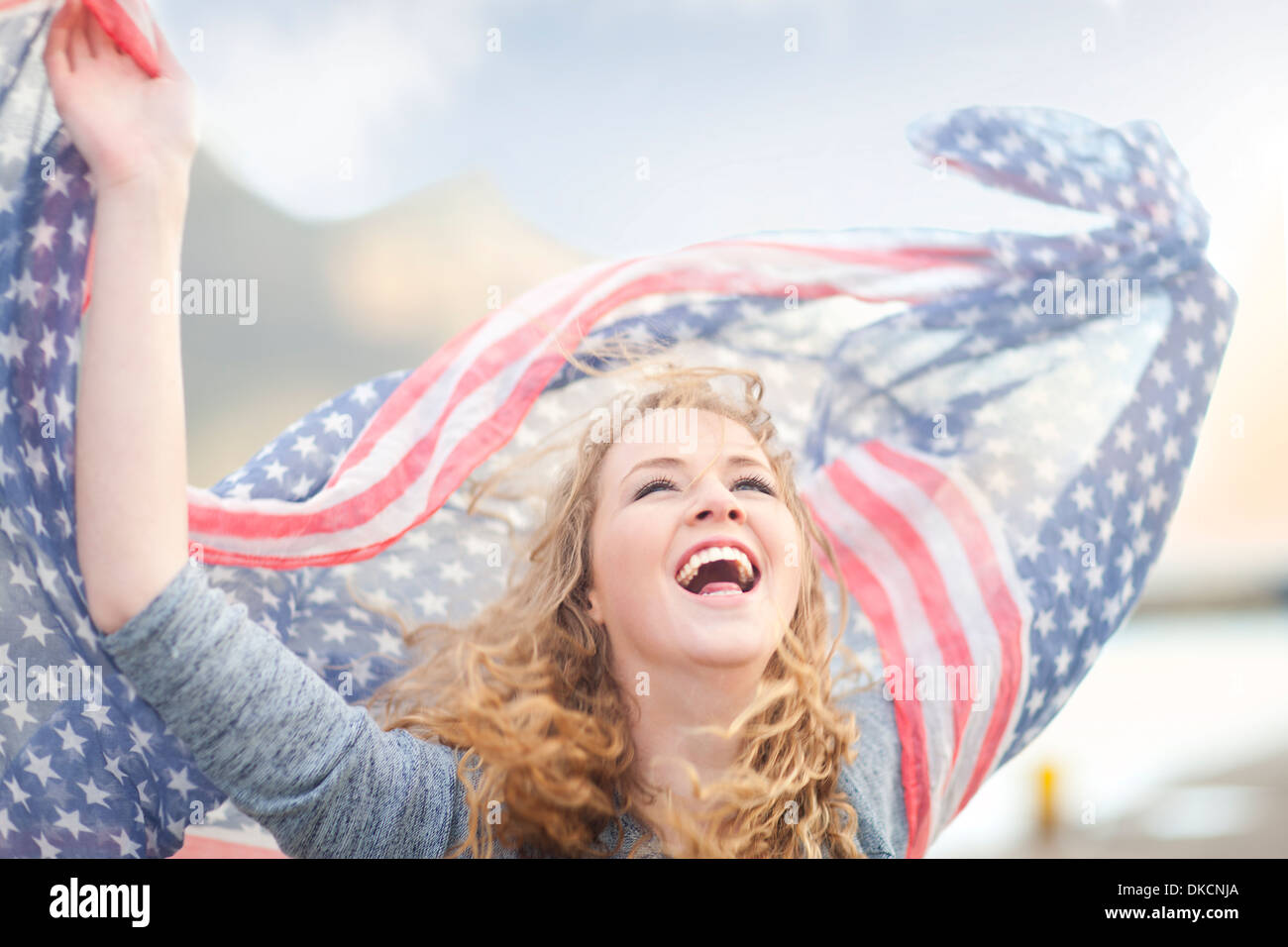 Woman waving with scarf of stars and stripes, Hout Bay, Cape Town, South Africa Stock Photo