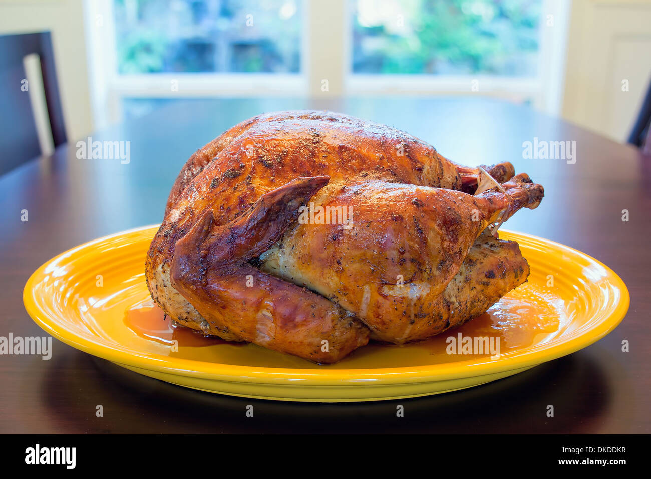 Cooked Whole Roast Turkey on Yellow Platter Sitting on Table for Thanksgiving Dinner Stock Photo